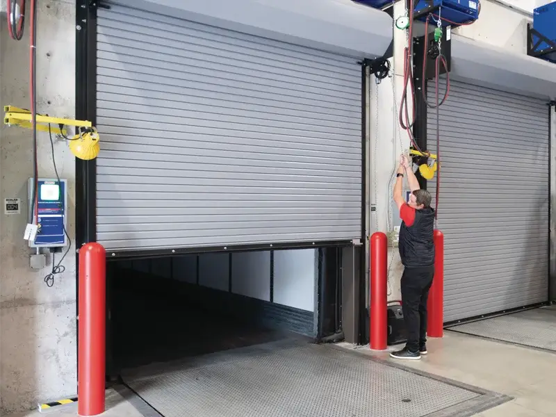Commercial garage door installation with technician operating rolling steel doors in an industrial setting, emphasizing safety and efficiency for business operations.