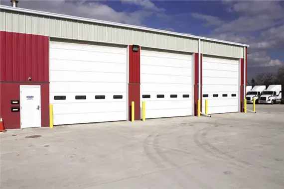 Commercial garage doors with sectional design, featuring a red and white color scheme, installed in a business facility, showcasing durability and security for various applications.