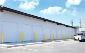 Commercial garage doors with white finish and yellow safety poles, showcasing Overhead Door Company of the Antelope Valley's durable installations for various business needs.