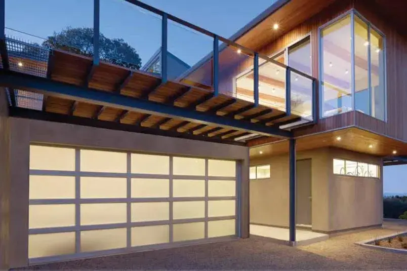 Modern aluminum garage door with sleek design and glass panels, complementing contemporary home architecture, illuminated at dusk.