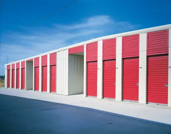 Rolling sheet doors in red, showcasing durable construction for commercial applications, designed for security and aesthetic appeal, with a clear blue sky in the background.