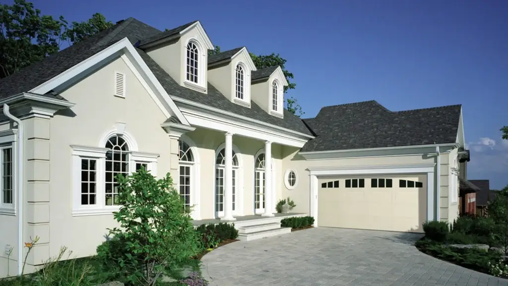 Elegant residential home exterior featuring a well-designed garage door, landscaped entrance, and clear blue sky, representing quality garage door solutions in Agua Dulce, CA.